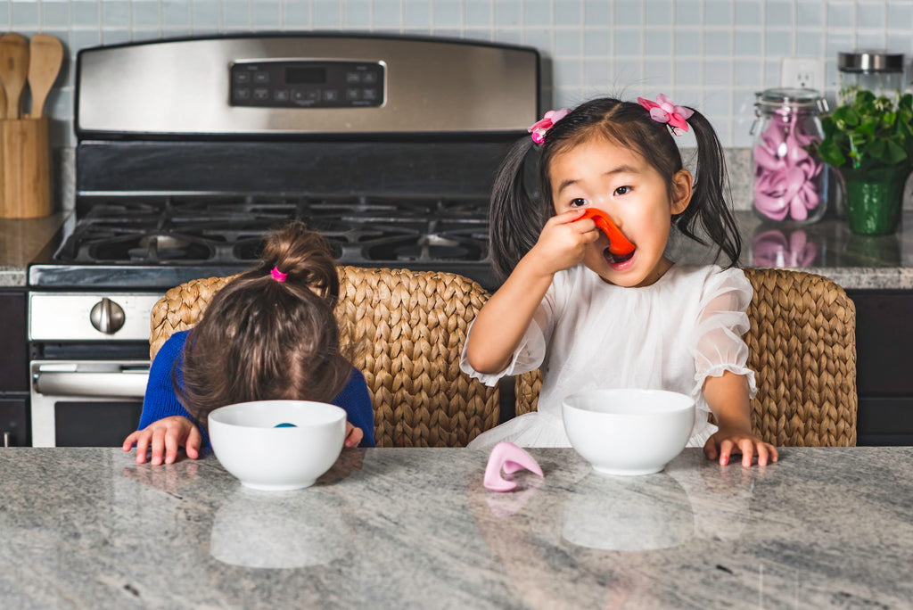 two little girls sitting at a kitchen counter eating 